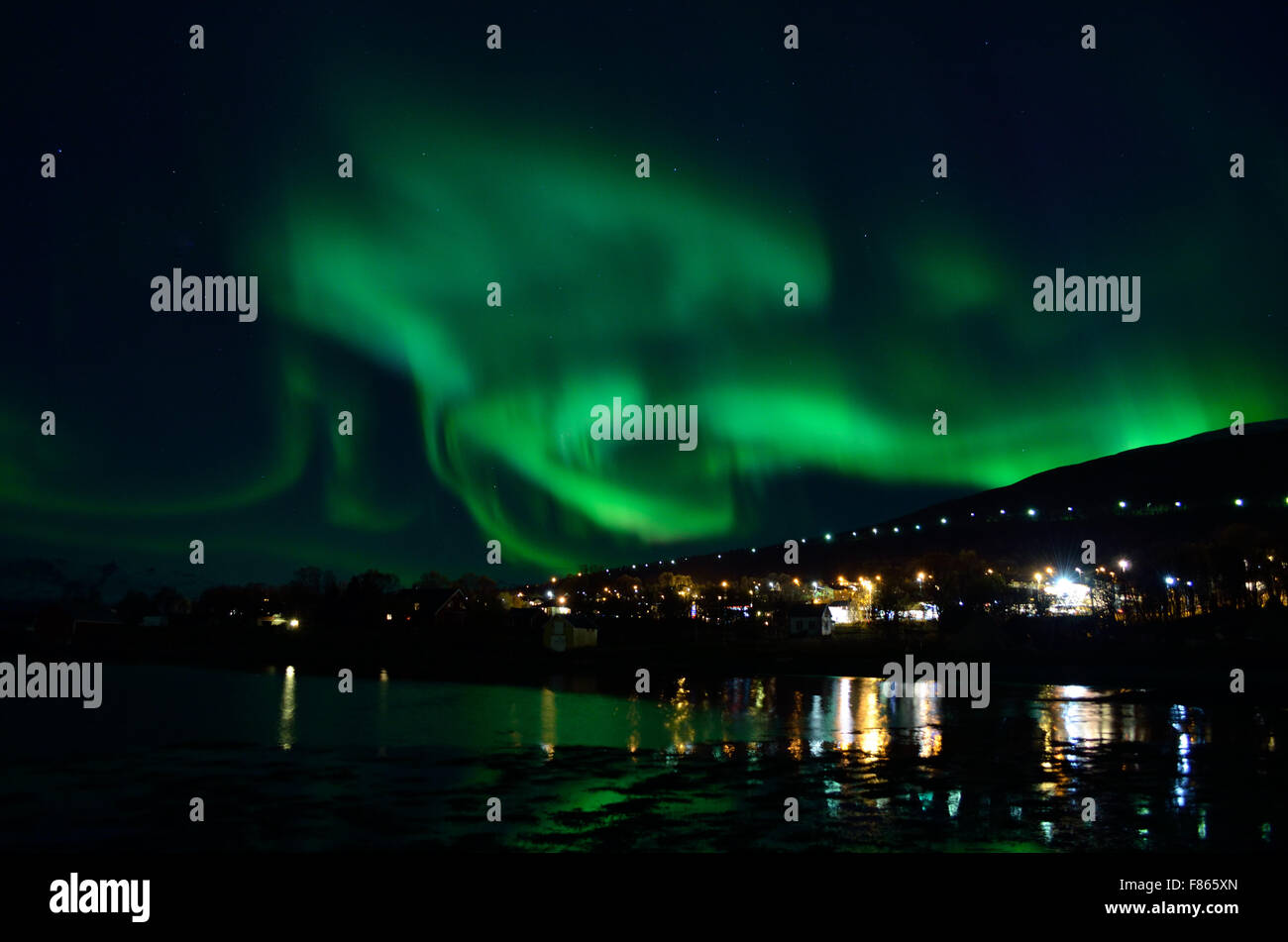 Forte aurora boreale oltre la collina e case Foto Stock