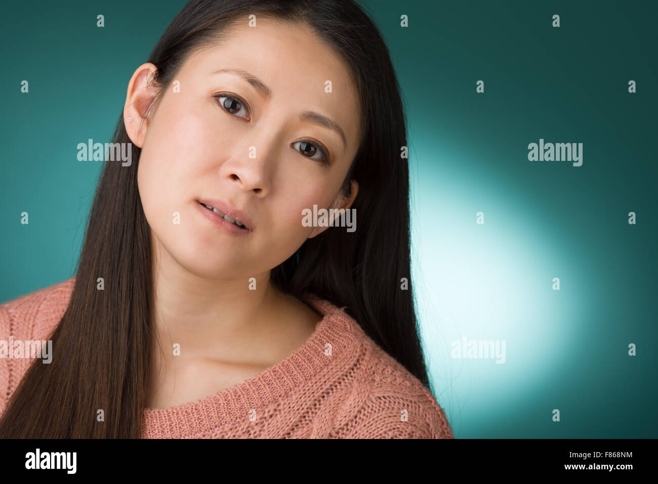 Un colpo di testa di una donna giapponese nel sentire presto 30s su un semplice sfondo verde. Foto Stock
