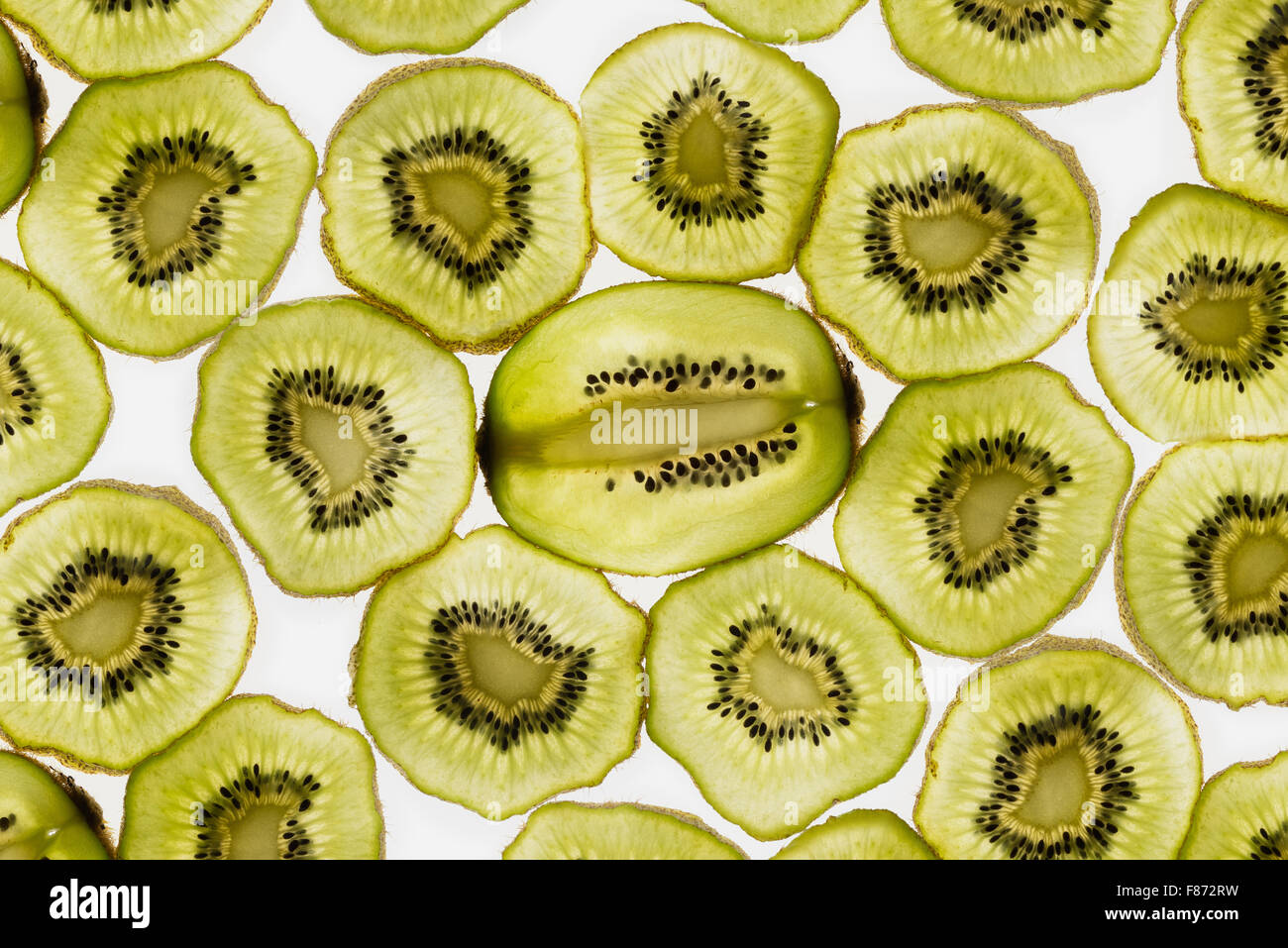 Esotica frutta kiwi retroilluminato in studio il taglio trasversale e longitudinale che mostra le sezioni interne di distribuzione di sementi intorno al nucleo centrale Foto Stock