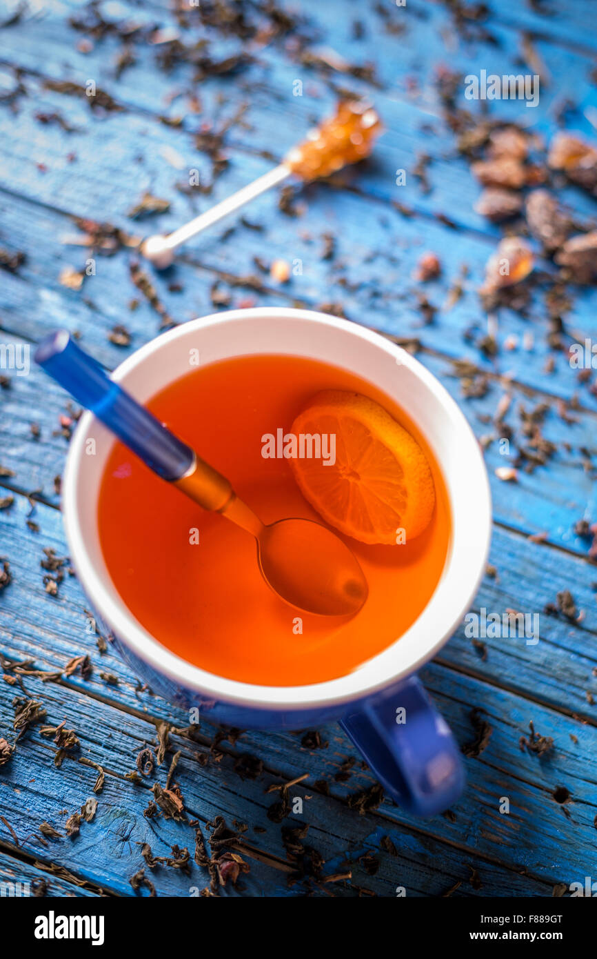 Tazza di tè con limone sul blu sullo sfondo di legno Foto Stock