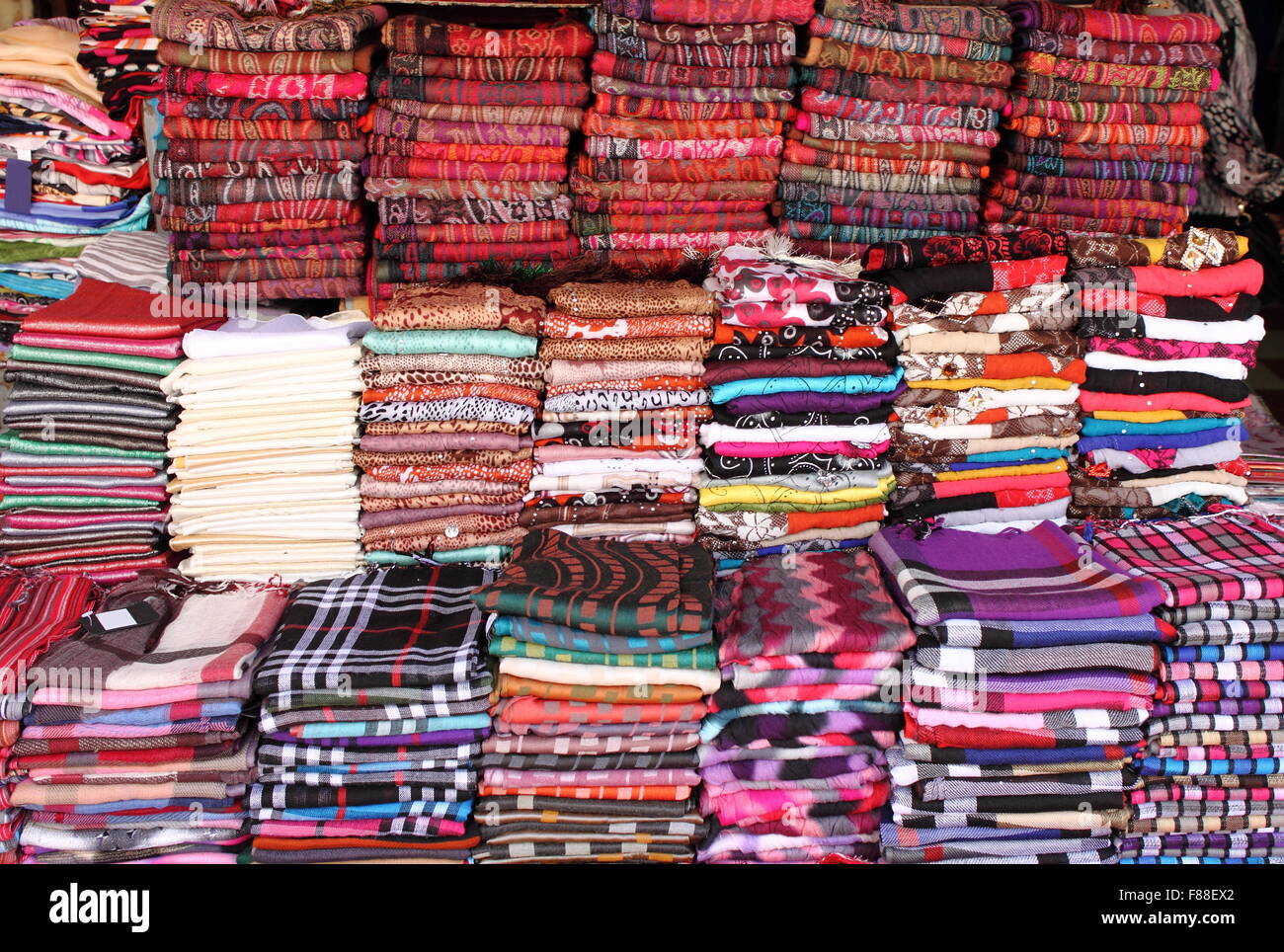 Pila di sciarpe pashmina per la vendita in un negozio di moda Foto Stock