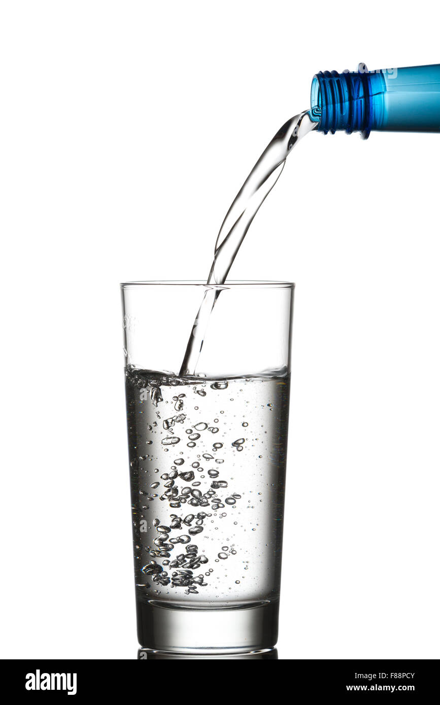 Versare acqua da un blu bottiglia di plastica in un bicchiere. Isolato su sfondo bianco Foto Stock