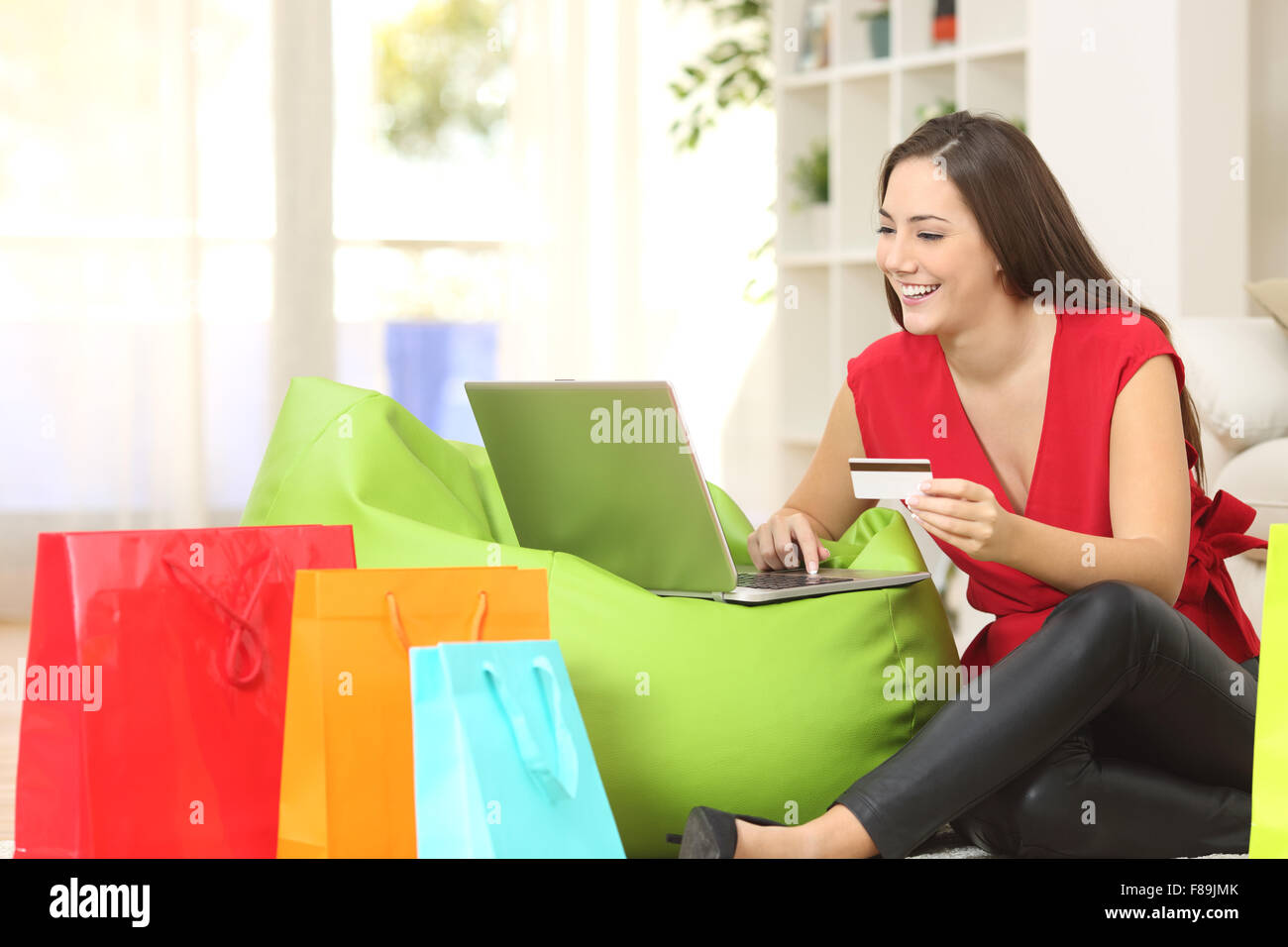 Donna acquisto online a casa con una carta di credito e più borse per lo shopping accanto a Foto Stock
