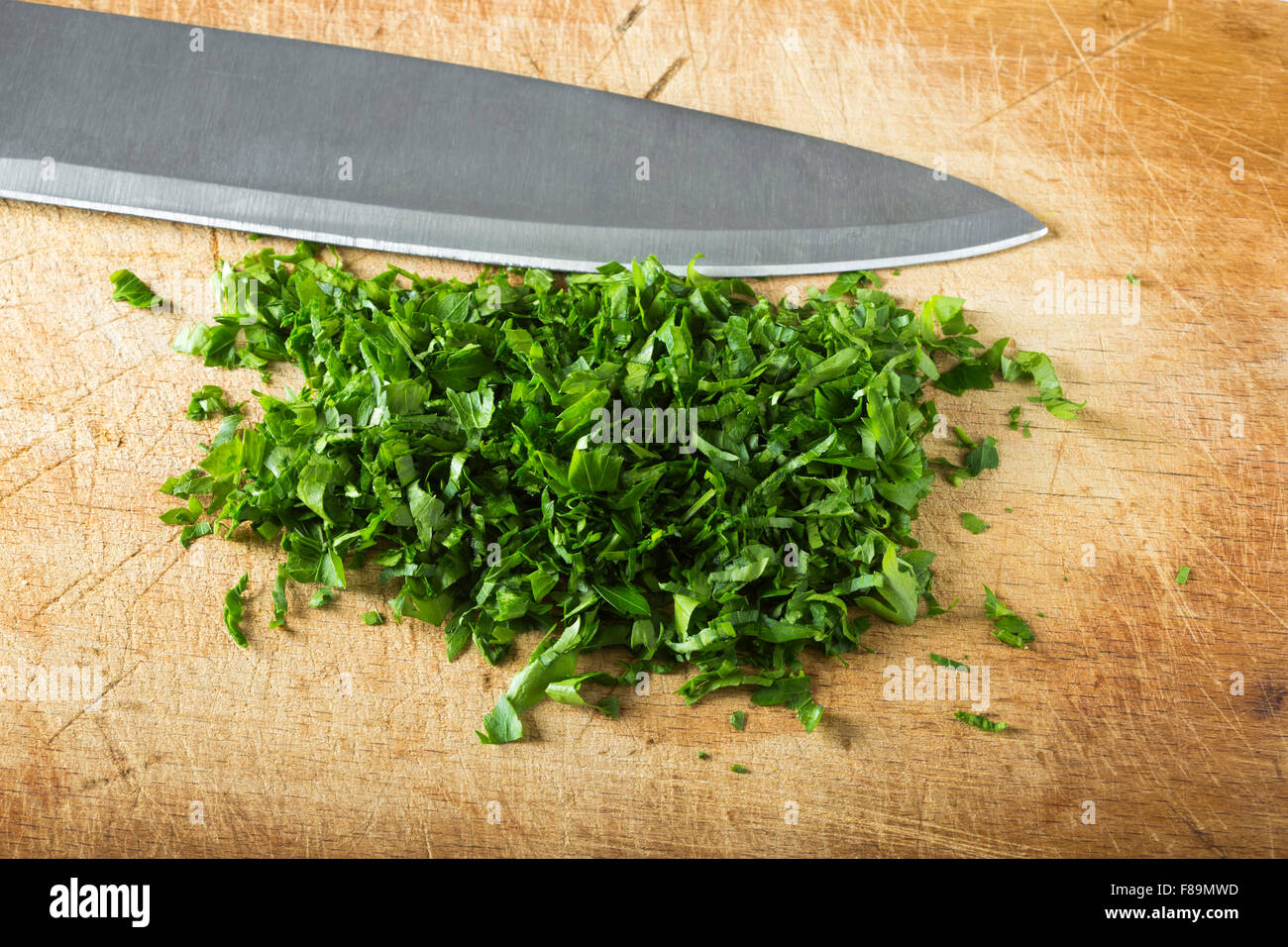 Prezzemolo tritato su legno tagliere con coltello Foto Stock