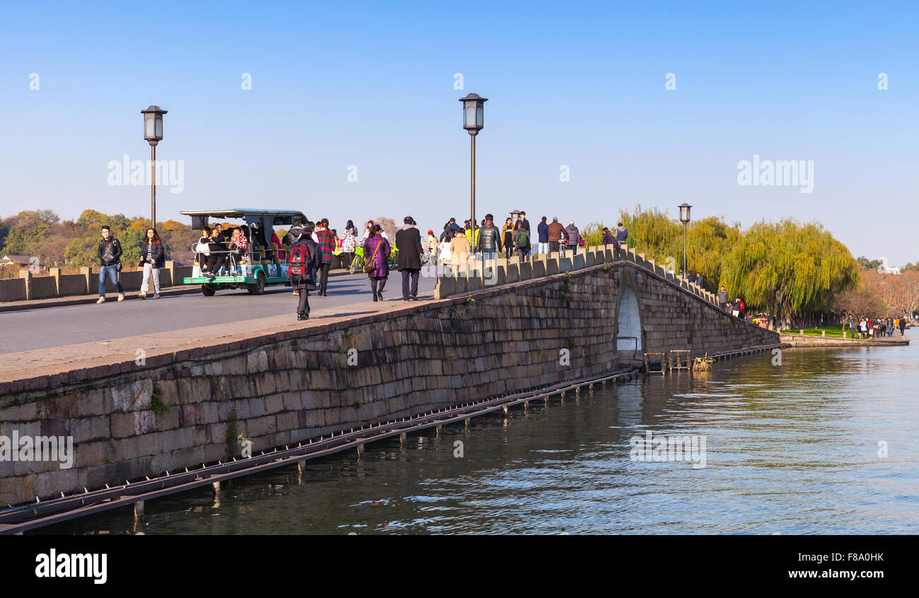 Hangzhou, Cina - 5 Dicembre 2014: Cinese il ponte di pietra sul Lago Ovest e costa. La gente comune a piedi nella famosa park Foto Stock