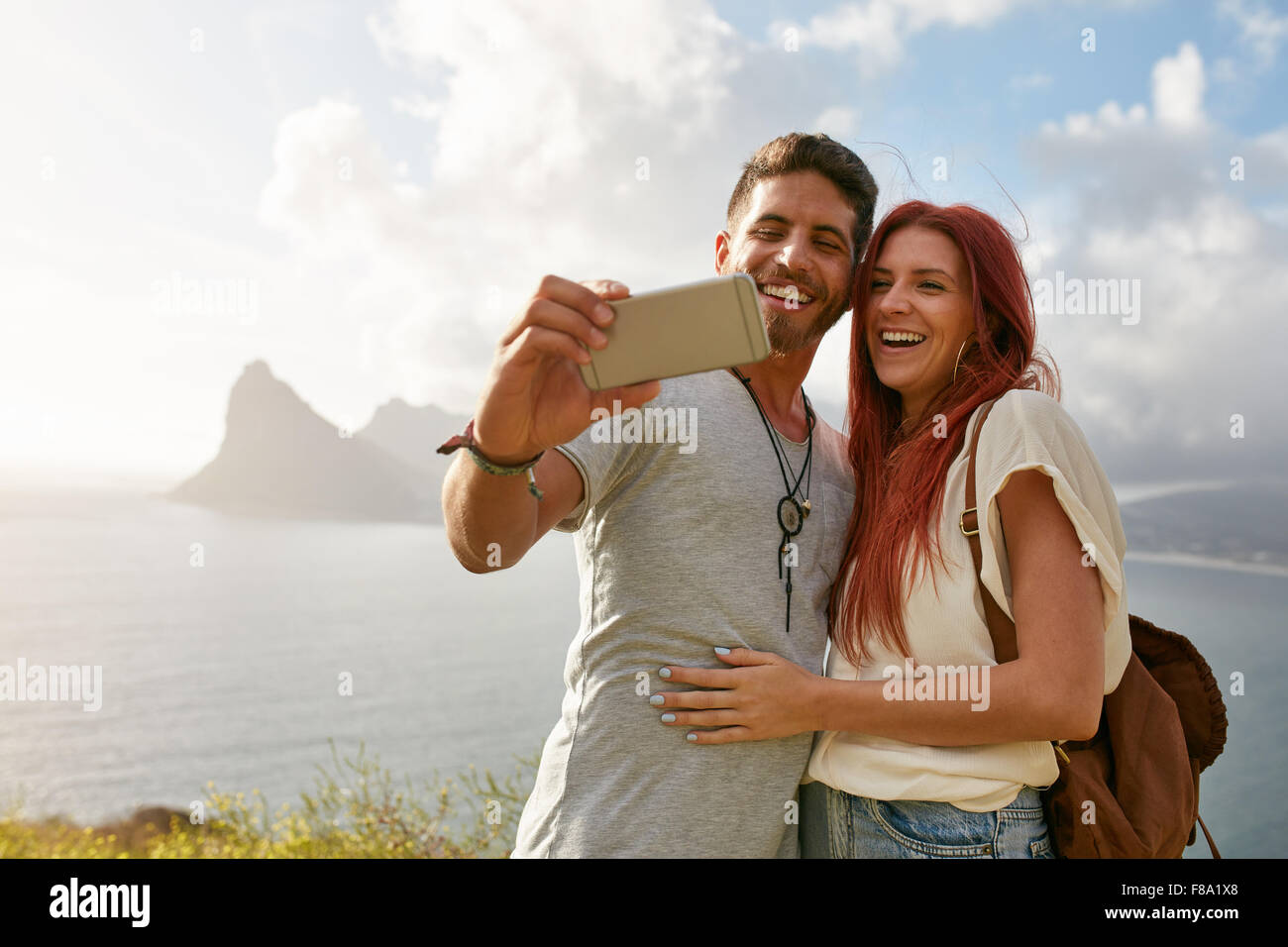 Sorridente giovane coppia amorevole tenendo ritratto di auto all'aperto in estate. Giovane uomo con la sua ragazza tenendo selfie con mobile pho Foto Stock