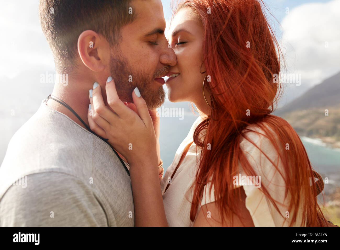 Immagine ravvicinata di affettuosa coppia giovane abbracciando e baciando all'esterno. Foto Stock