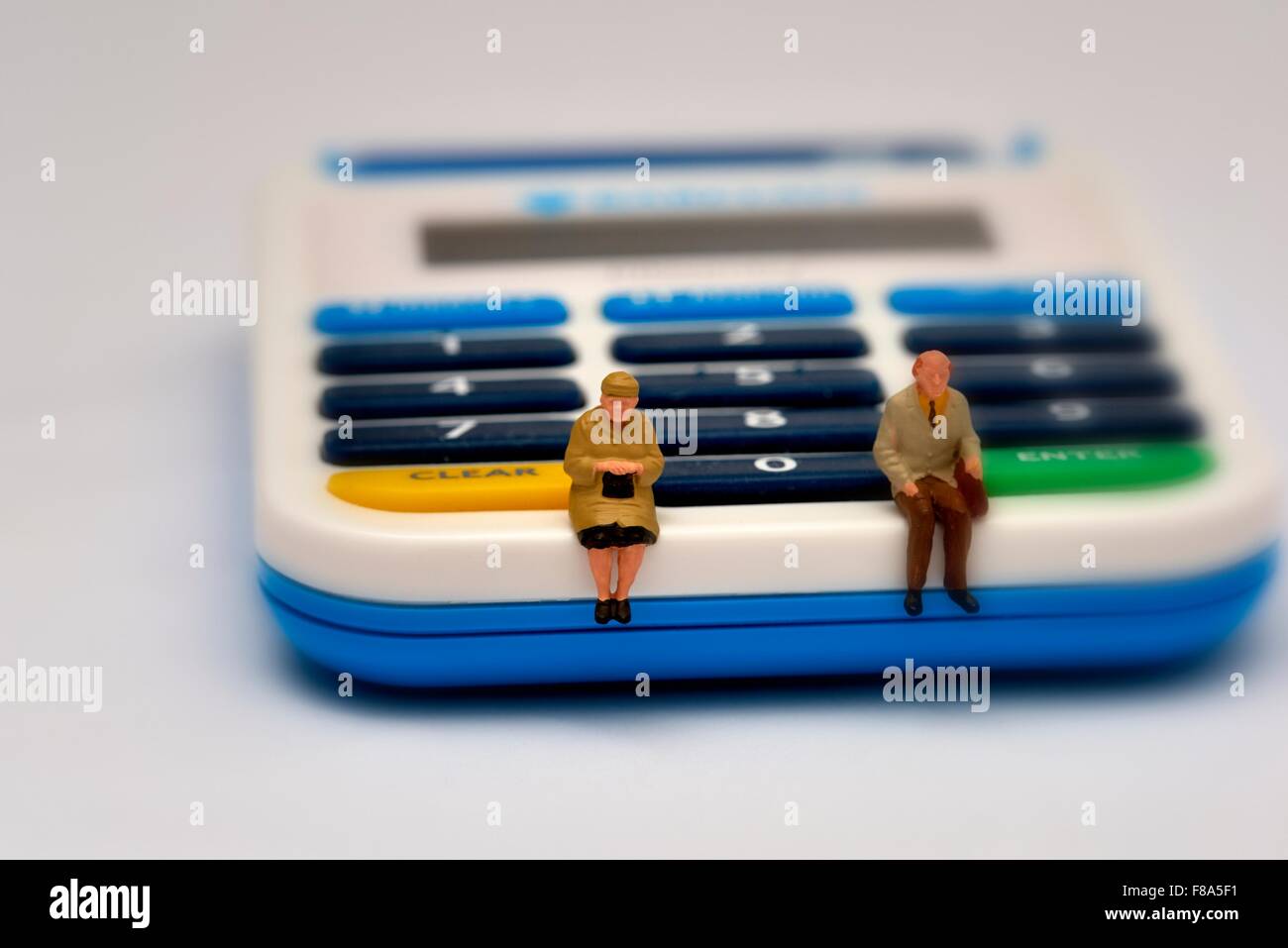 Due pensionato in miniatura figure seduti su un pin macchina sentinella Foto Stock