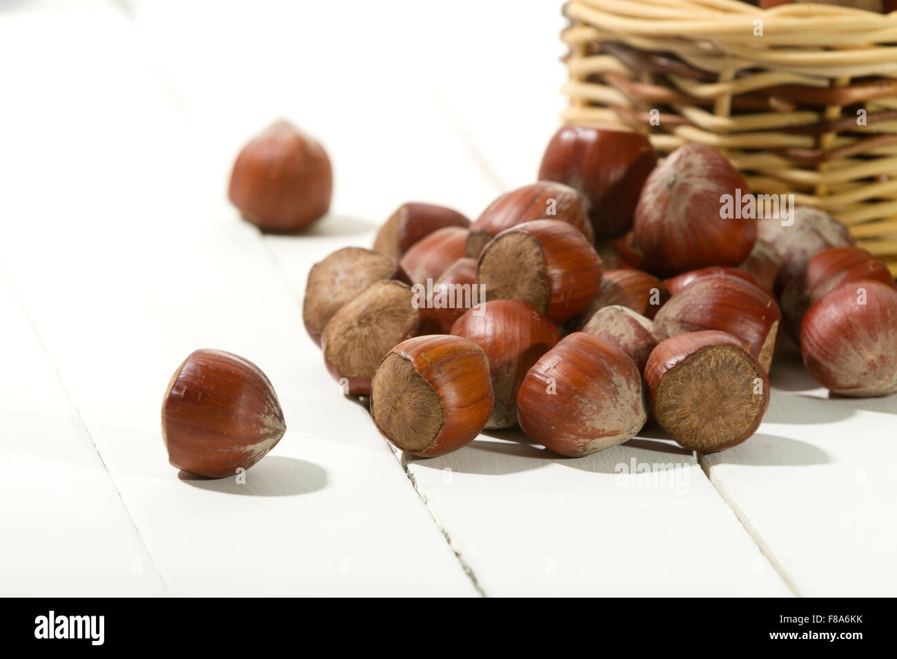 Le nocciole su un tavolo bianco con un cestello Foto Stock