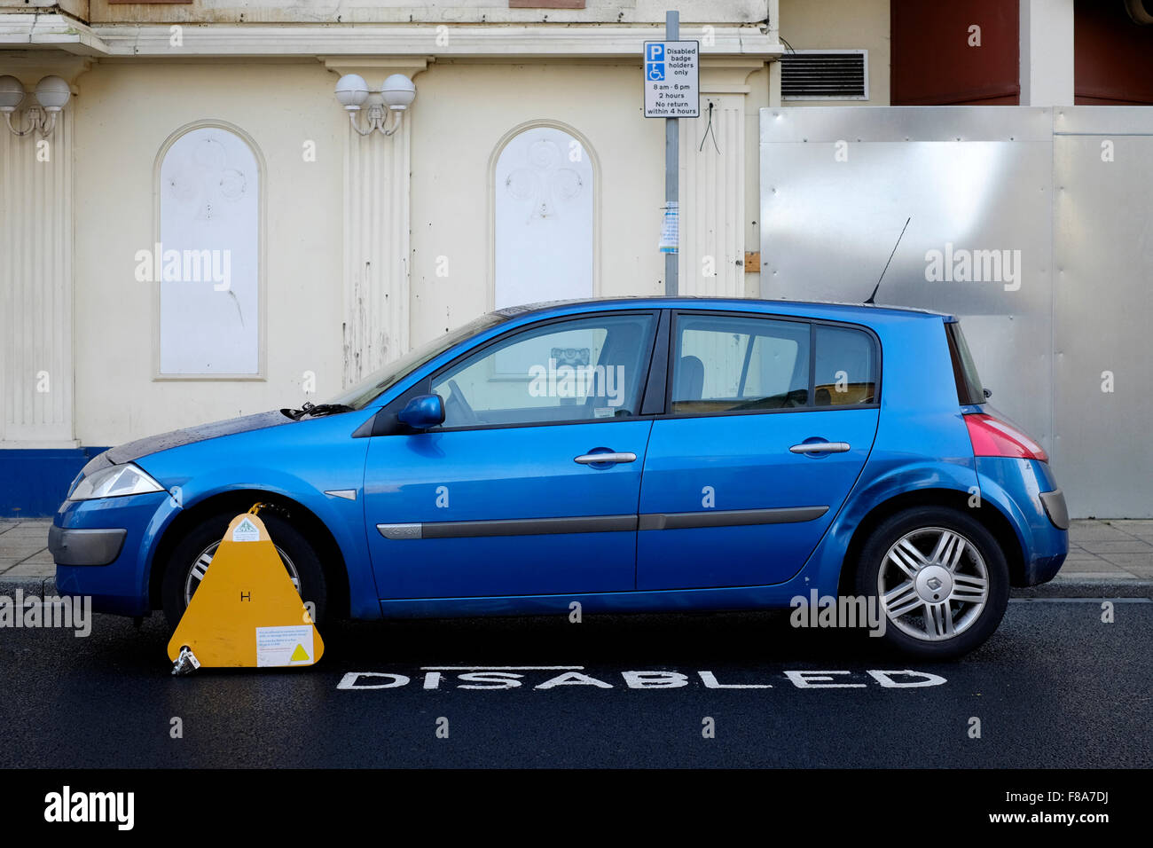 Ruota bloccata auto parcheggiate in sosta nella baia di disabili in un urbano area dello shopping England Regno Unito Foto Stock