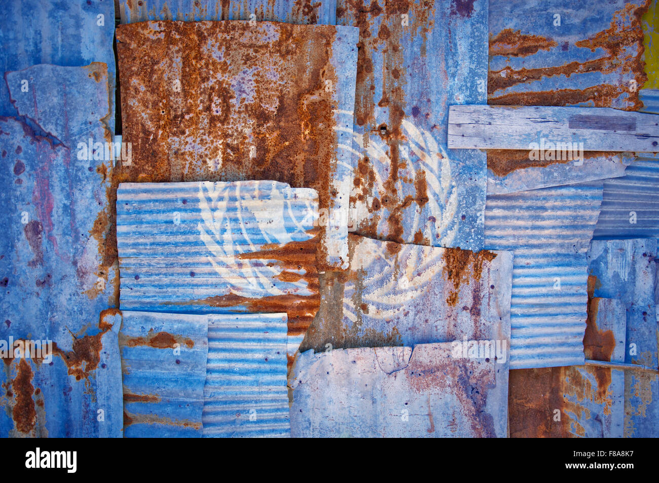 Un abstract immagine di sfondo di bandiera delle Nazioni Unite dipinta su di rusty ferro corrugato fogli sovrapposti per formare una parete Foto Stock
