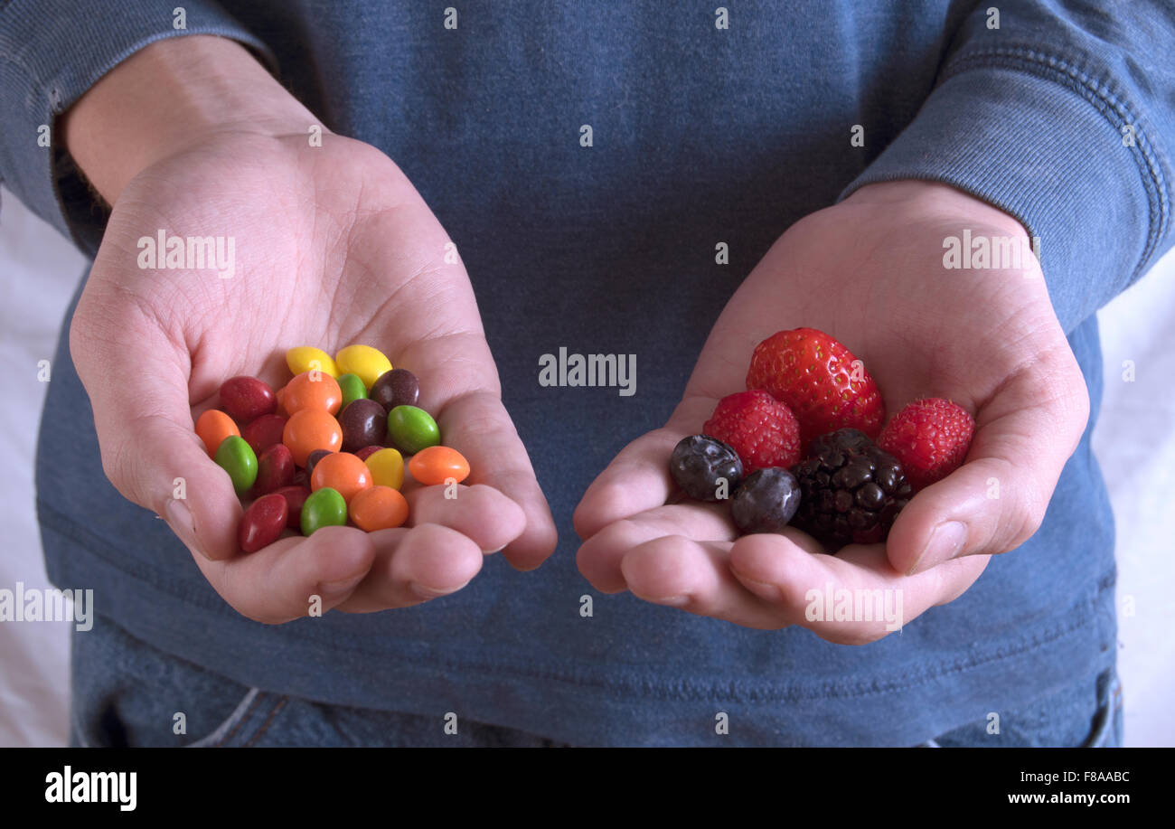 Caramelle e frutta in mani Foto Stock
