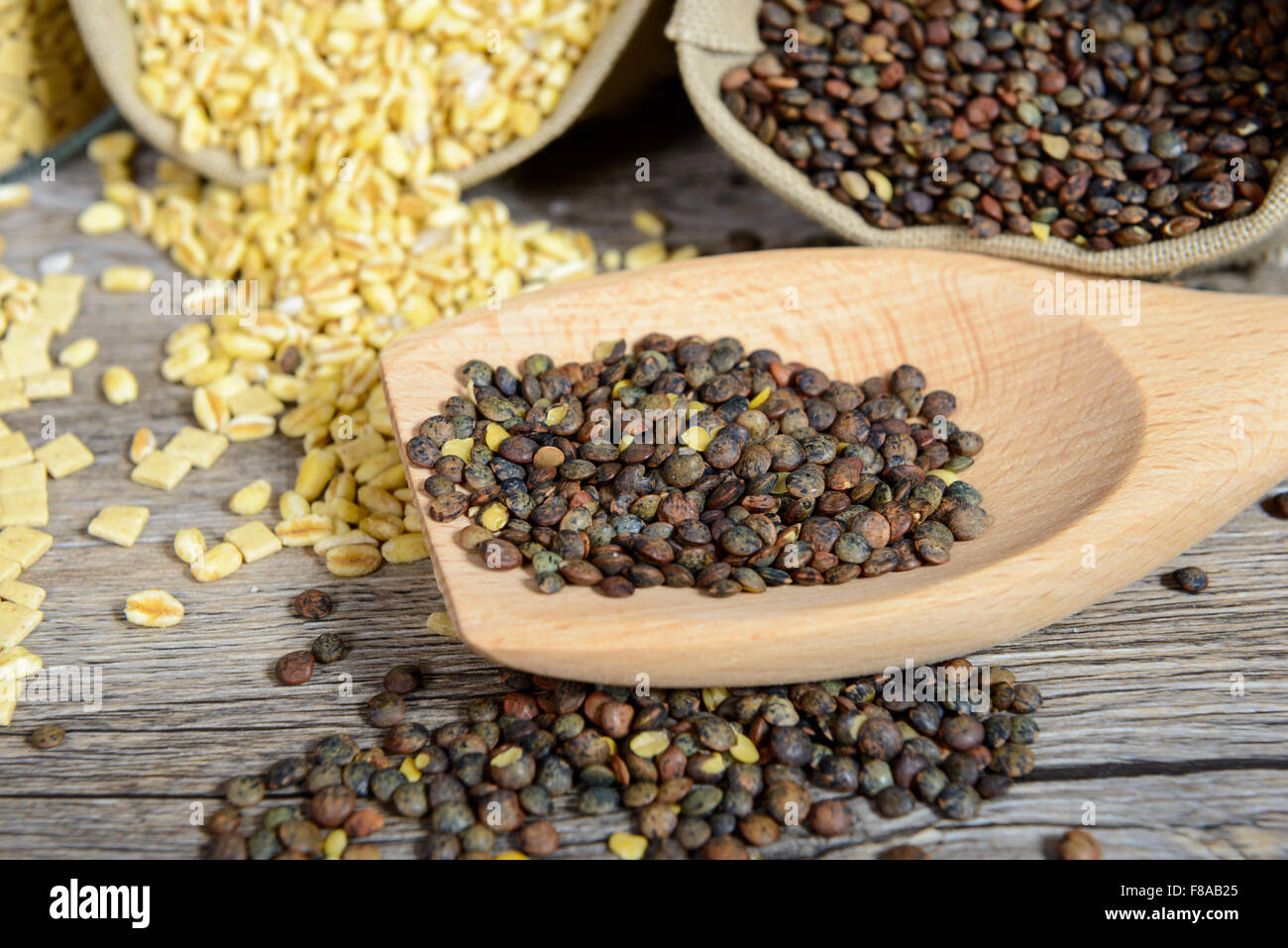 Un incontro ravvicinato con un cucchiaio di legno pieno di lenticchie Foto Stock