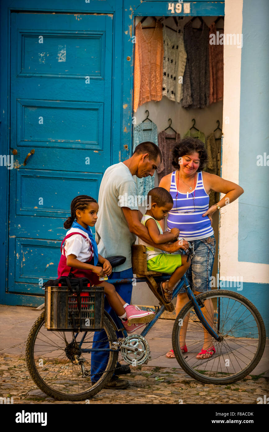 Scena di strada con i bambini e la bicicletta nella città vecchia di Trinidad, famiglia bicicletta, due bambini su una bicicletta, negozio di abbigliamento, Foto Stock