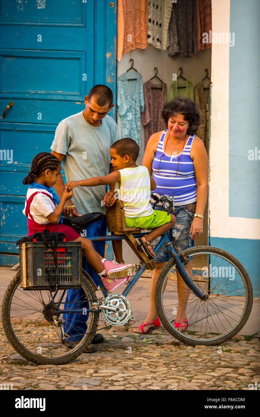 Scena di strada con i bambini e la bicicletta nella città vecchia di Trinidad, famiglia bicicletta, due bambini su una bicicletta, negozio di abbigliamento, Foto Stock