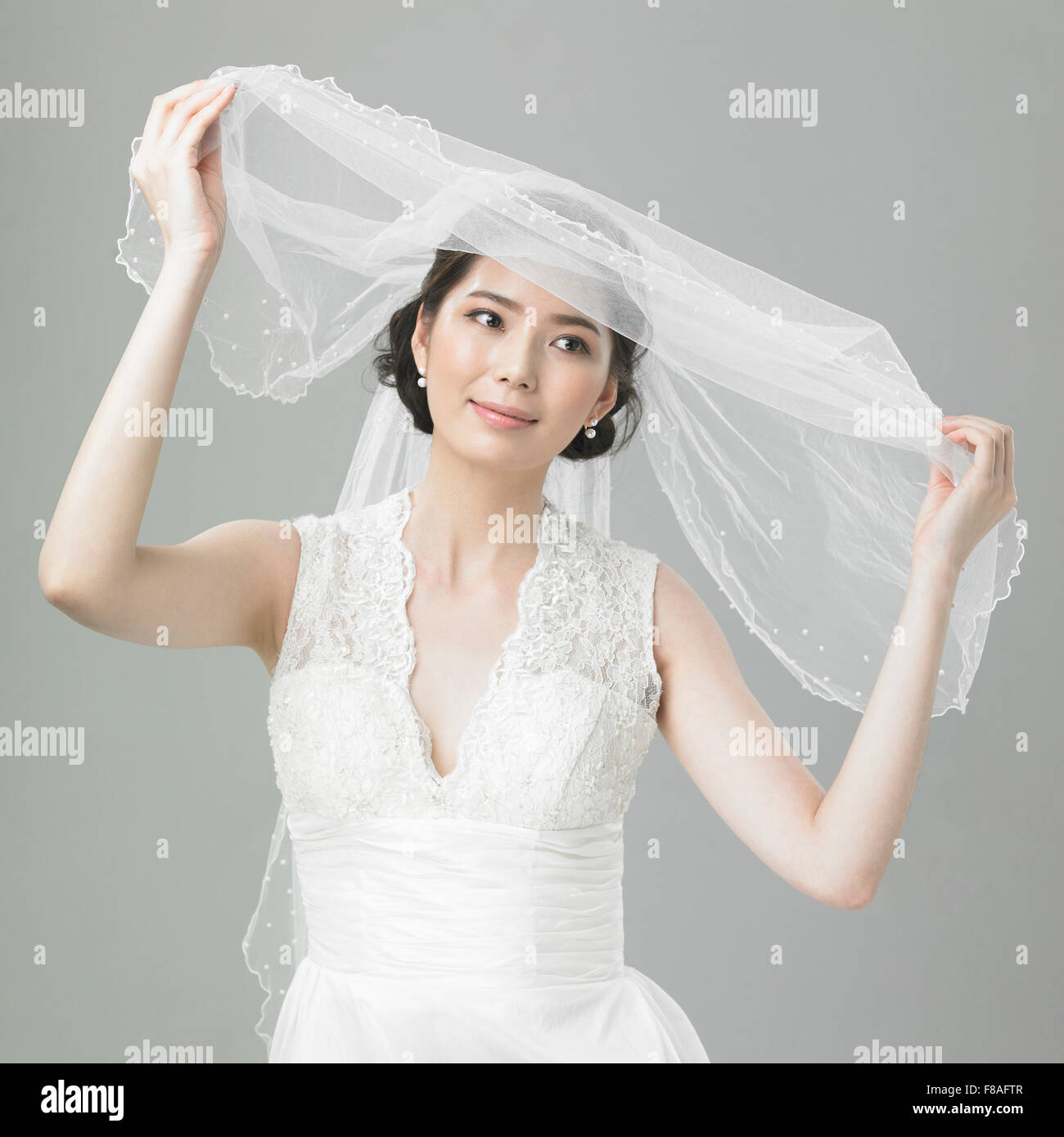 La donna in abito da sposa azienda e apertura del velo nuziale Foto Stock