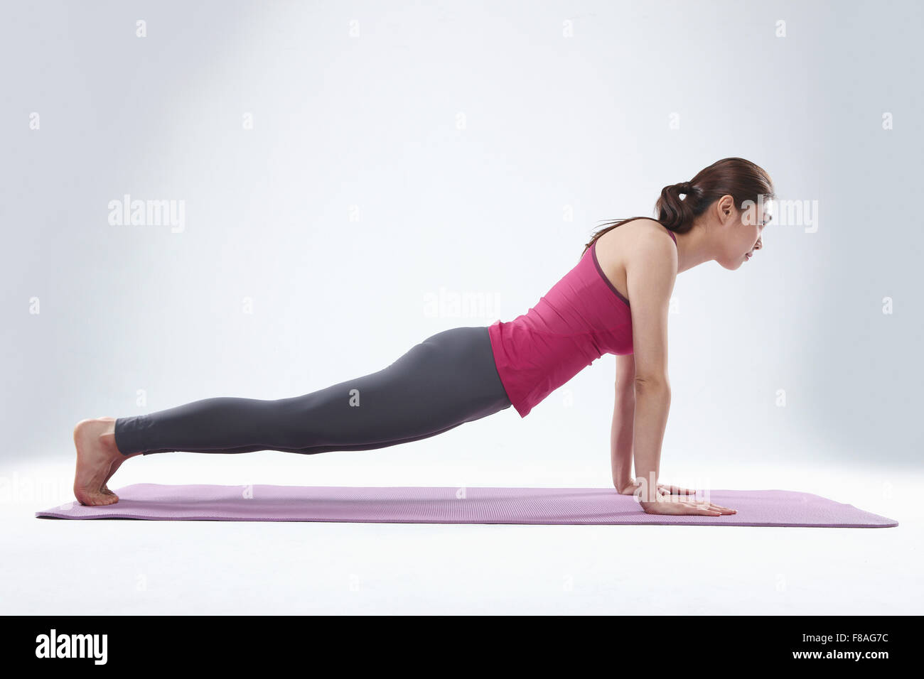Donna sul materassino yoga facendo ups push Foto Stock