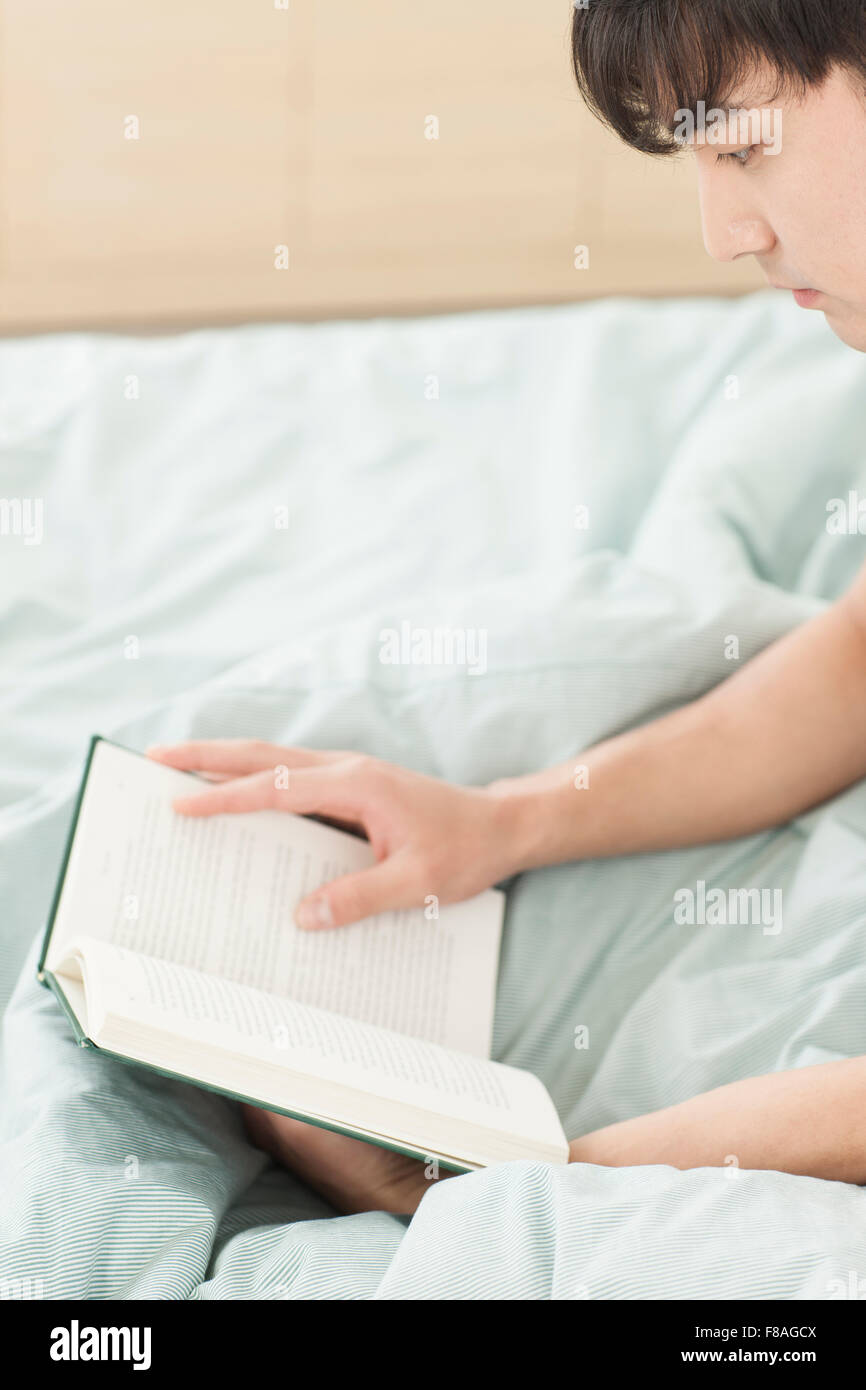 L'uomo la lettura di un libro a letto Foto Stock