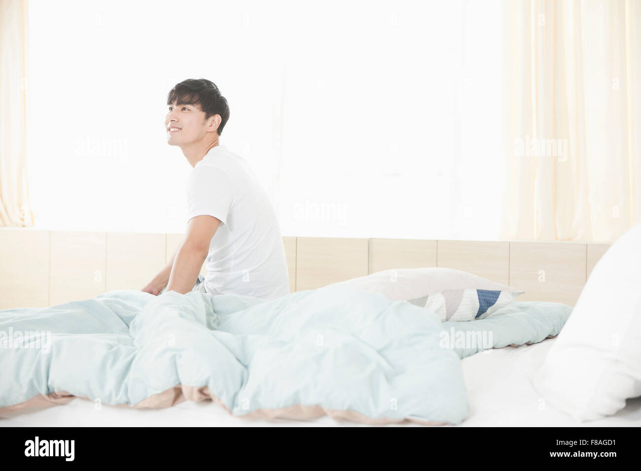 Uomo seduto su un letto con lo sguardo verso l'alto Foto Stock