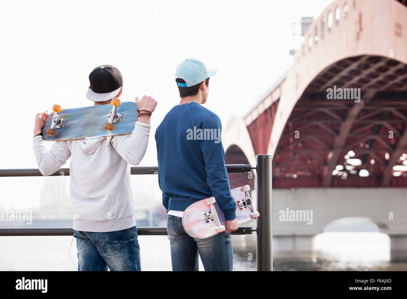 Due uomini con i loro skateboard in piedi dietro il recinto sotto il ponte Sungsan Foto Stock