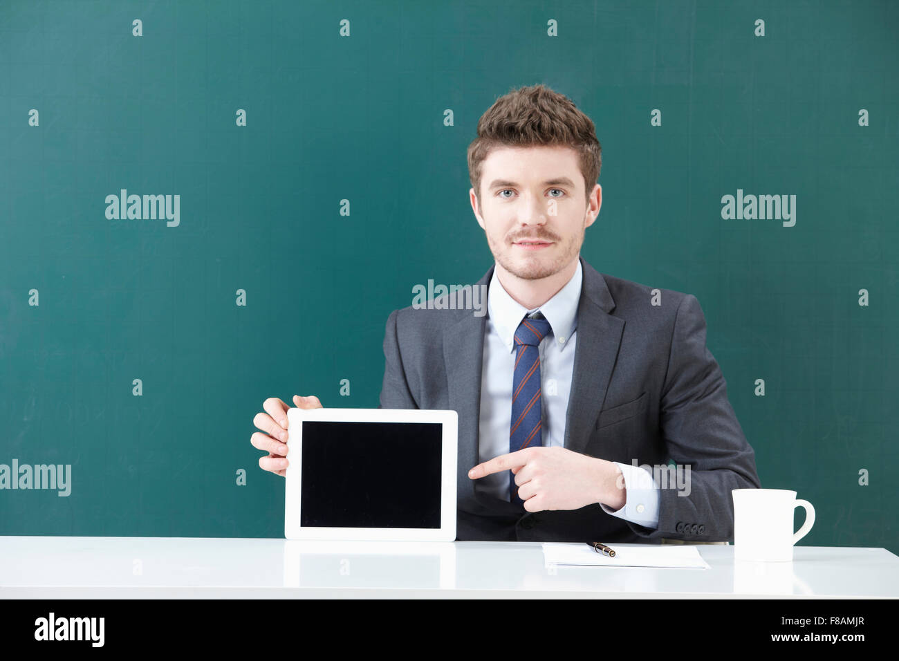 Ritratto di imprenditore che mostra un tablet e rivolta verso di essa con un dito lo sguardo sul lato anteriore Foto Stock