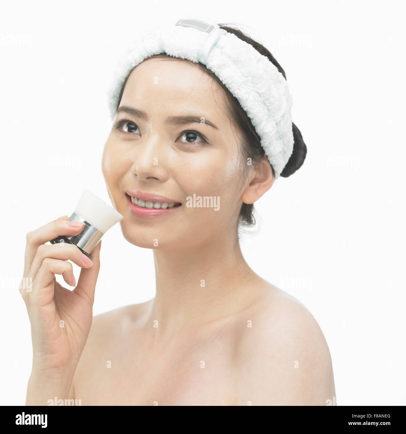 Ritratto di sorridente donna coreana avendo cura della pelle con un pennello cercando Foto Stock
