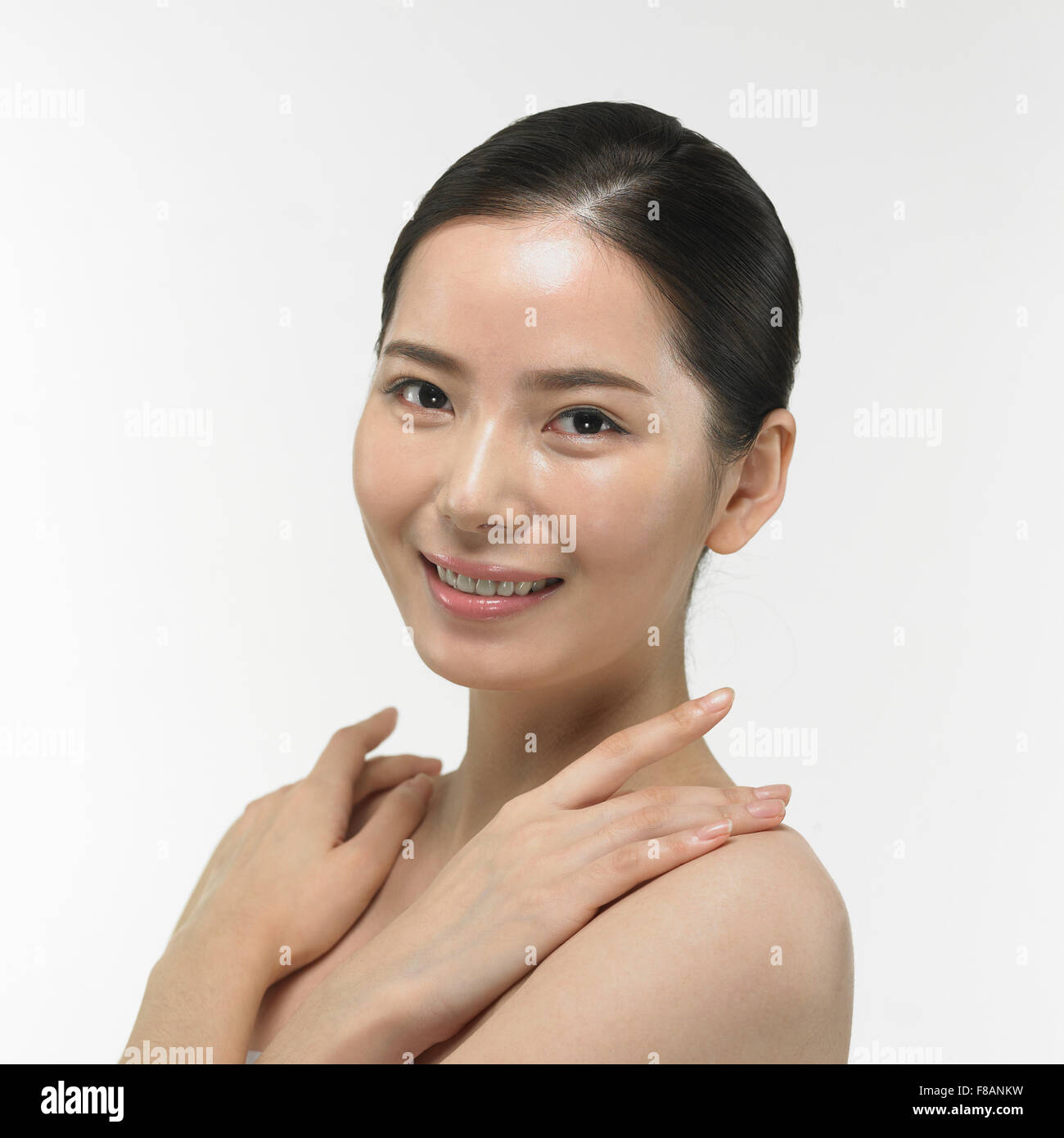 Ritratto di donna coreana fissando davanti ponendo le mani sulle spalle e con un grande sorriso Foto Stock