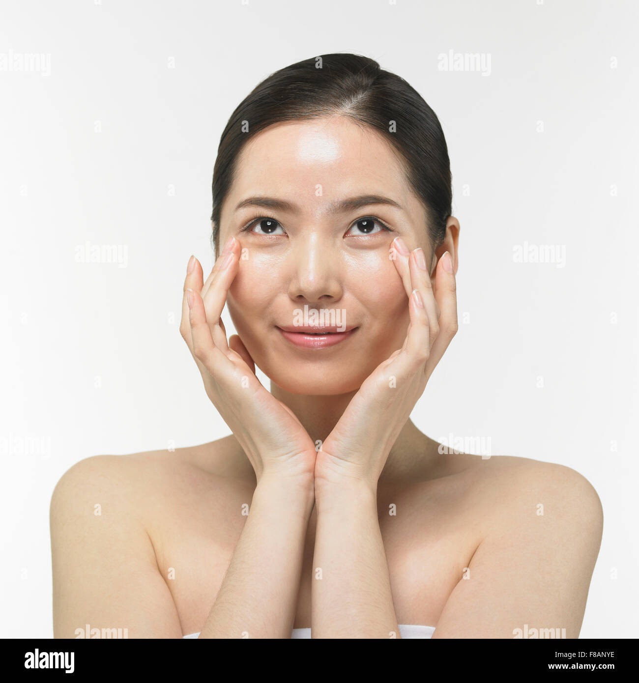 Ritratto di donna Coreana di toccare gli angoli dei suoi occhi che guardano in alto con un sorriso Foto Stock
