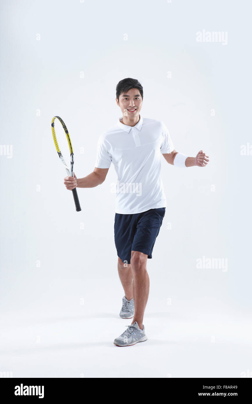 Uomo sorridente in piedi i bracci di apertura con una racchetta da tennis e un pugno Foto Stock