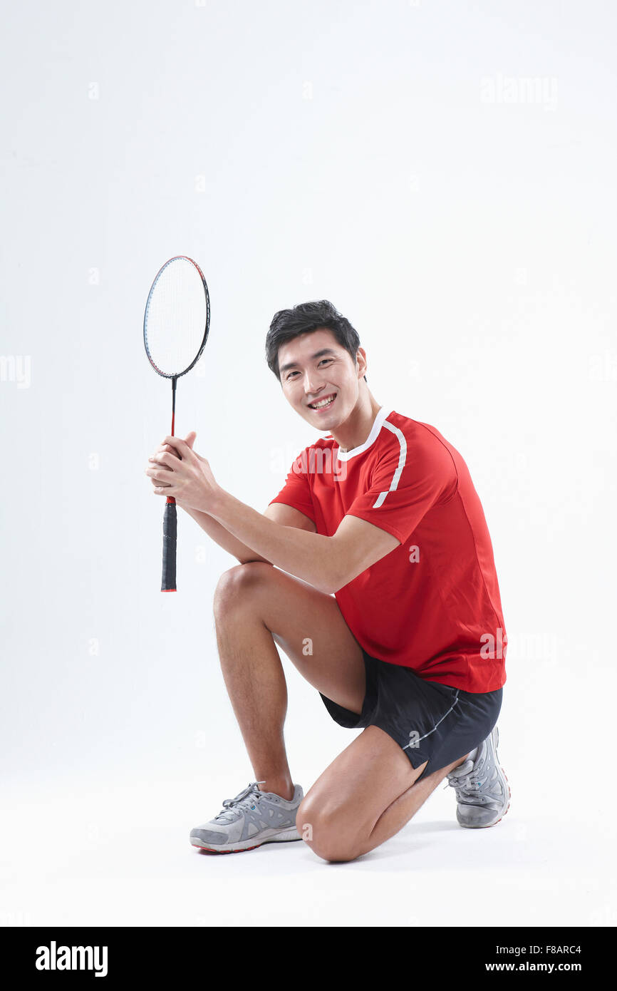 Uomo seduto mani di piegatura con un campo di badminton racchetta fissando sulla parte anteriore Foto Stock