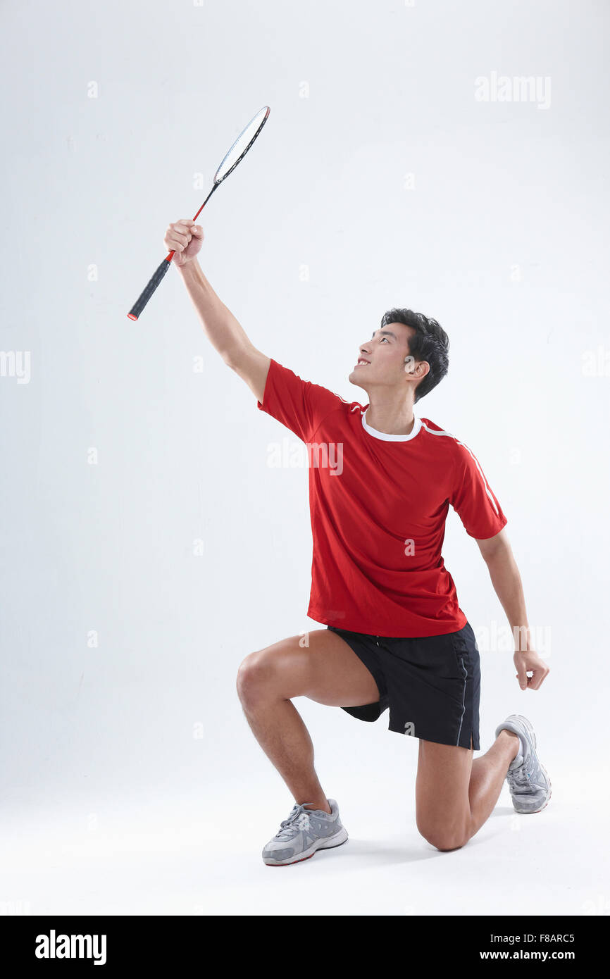 Uomo seduto e sollevamento di un campo di badminton racchetta cercando Foto Stock
