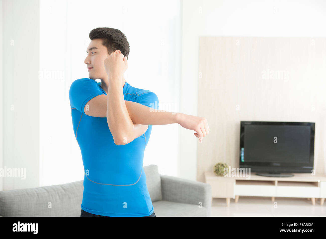 Ritratto di uomo bracci di estensione guardando indietro nel soggiorno Foto Stock