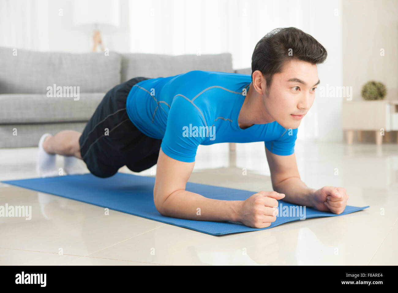 Uomo disteso a faccia in giù e stretching sul tappeto in salotto Foto Stock