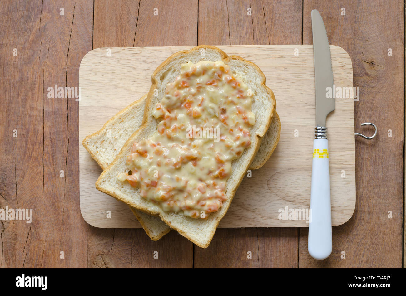 Un overhead close up di fette di pane appena sfornato pagnotta di pane integrale su un tagliere la posa su un vecchio rustico tavolo picnic Foto Stock