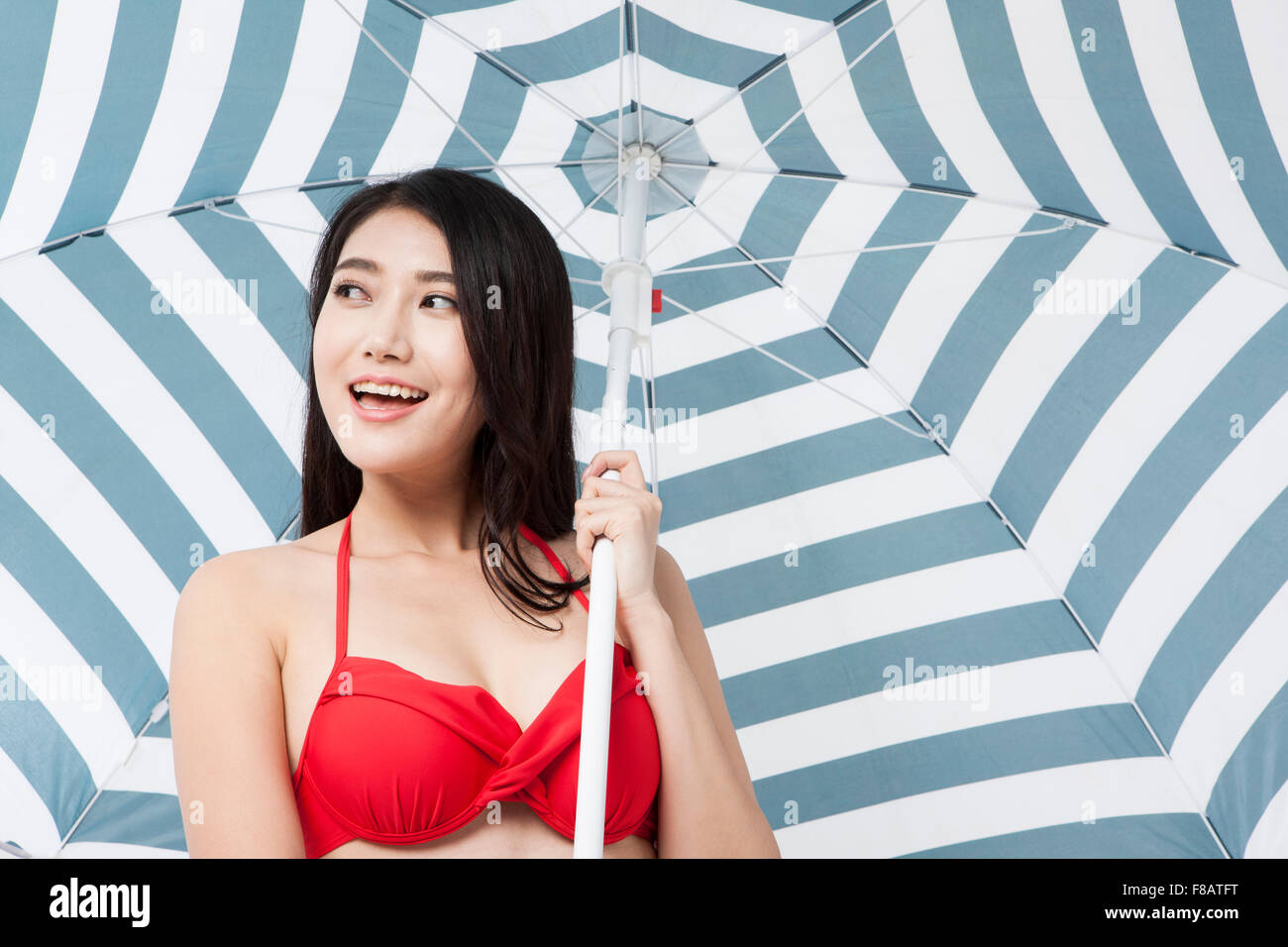 Ritratto di donna in bikini tenendo un ombrellone con un sorriso Foto Stock
