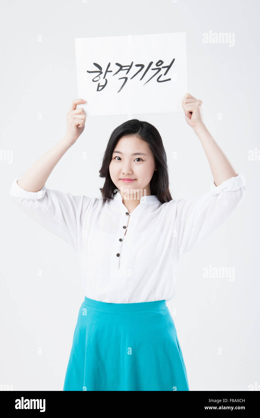 Ritratto di Korean highschool girl mostra allegro messaggio per collegio nazionale esame di entrata sulla carta Foto Stock