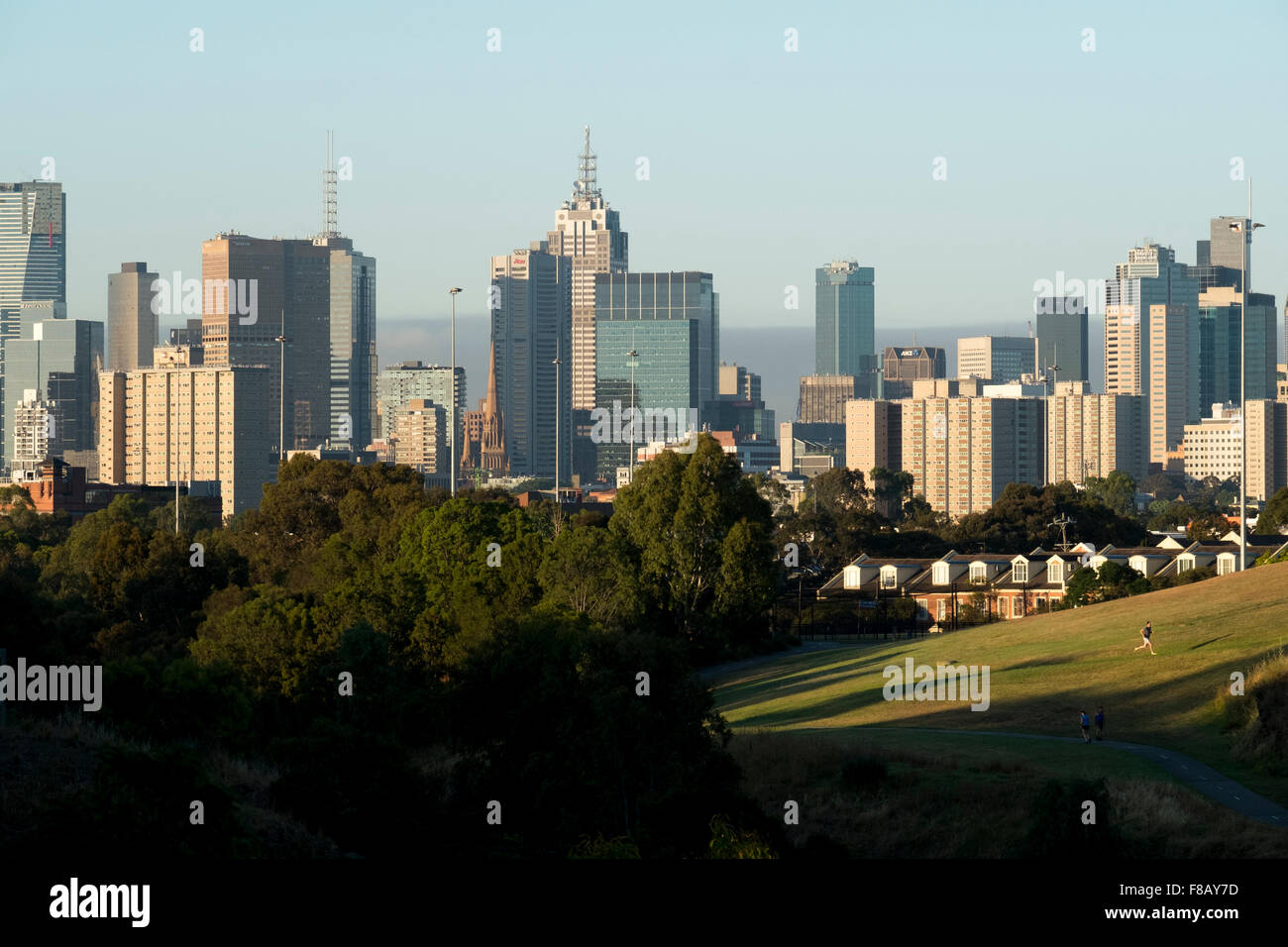 Un runner esercita su Clifton Hill, riserva Hall di fronte dello skyline della citta' di Melbourne. Foto Stock