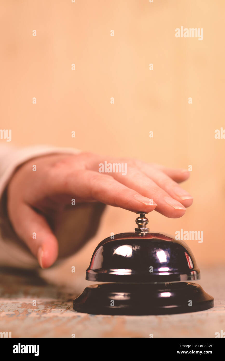 Suoneria donna servizio hotel bell sulla reception, dai toni rétro immagine, il fuoco selettivo Foto Stock