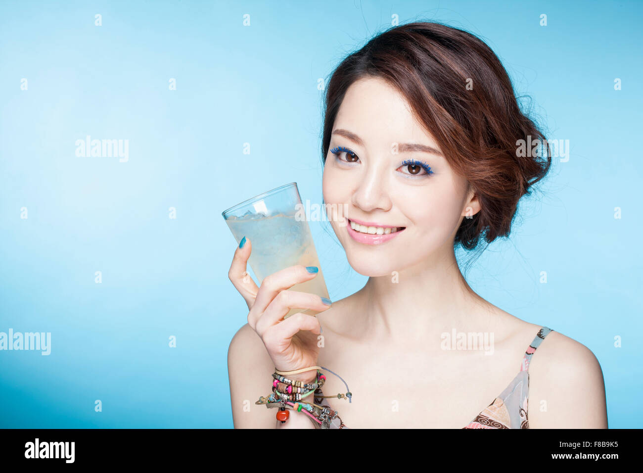 Donna in abiti estivi tenendo un bicchiere di bibita e sorridente Foto Stock