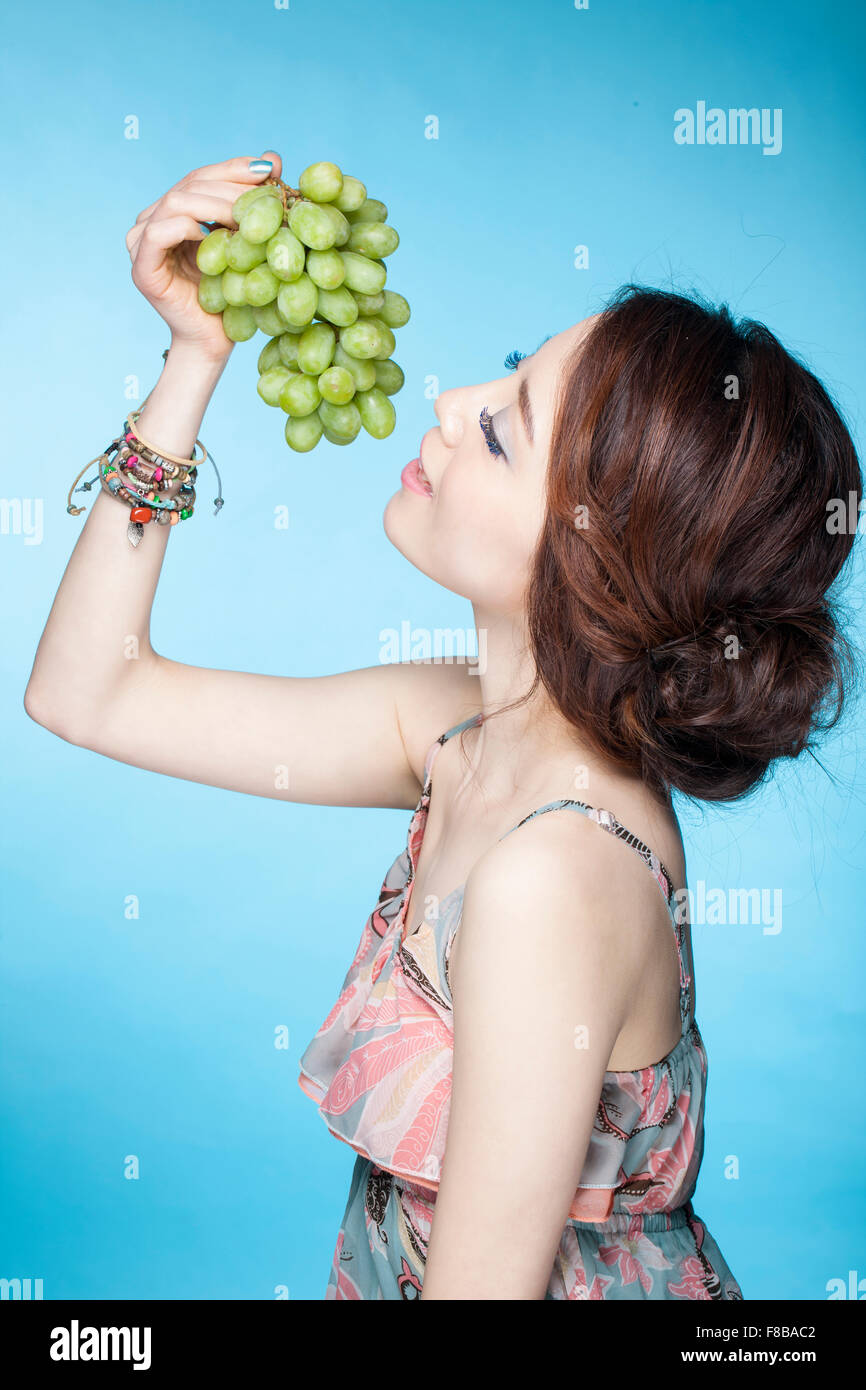 Donna in estate usura uva da mangiare con gli occhi chiusi Foto Stock