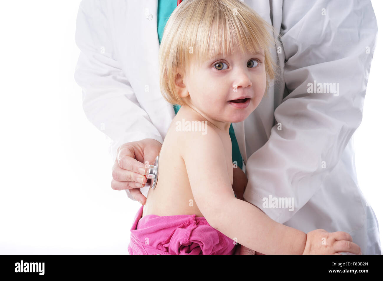 Il medico esamina il toddler bambino e ascolto di cuore e polmoni con stetoscopio. La bambina è felice, isolato su bianco Foto Stock