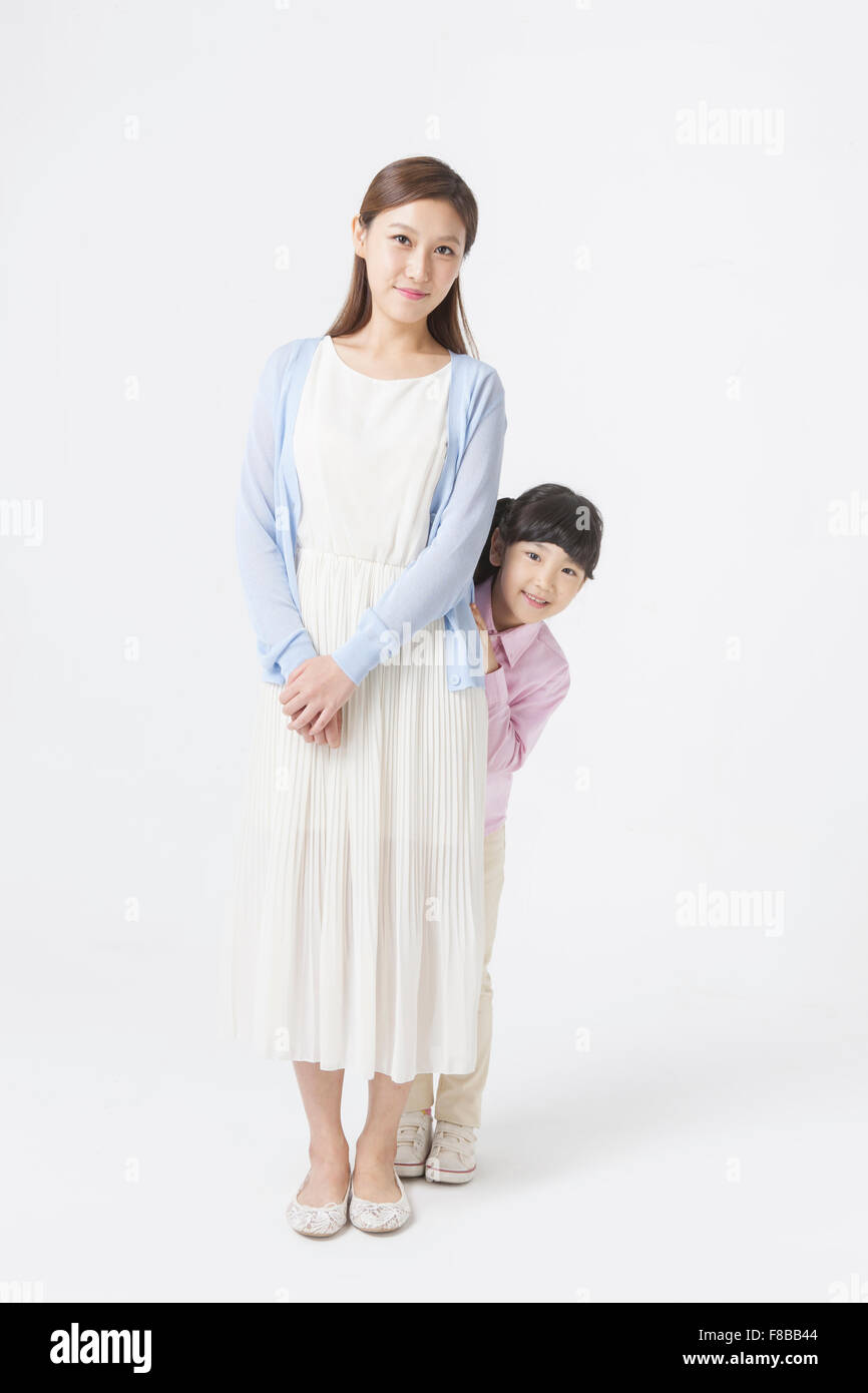Giovane ragazza Coreana di nascondersi dietro la sua madre sia sorridente Foto Stock