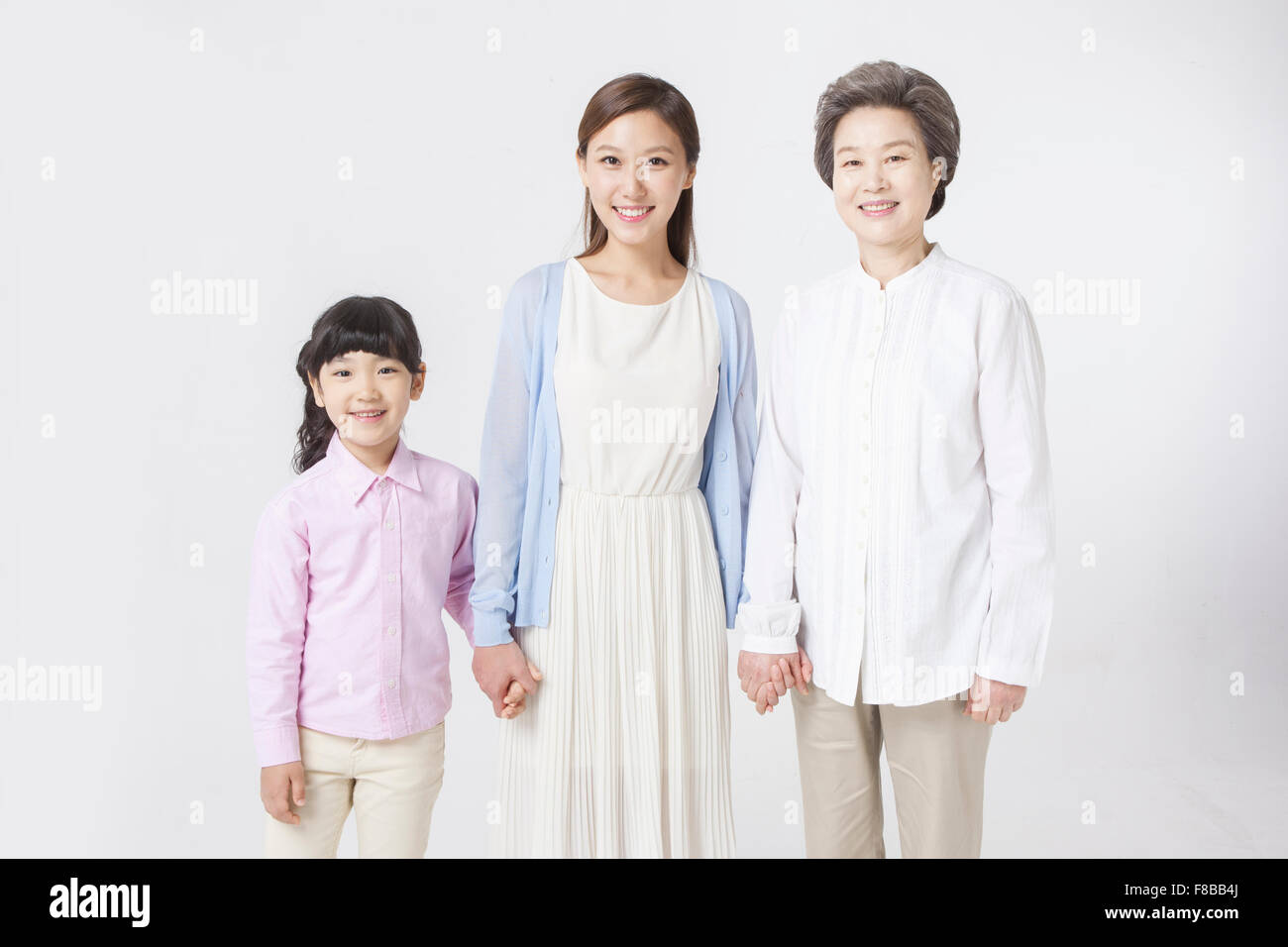 La madre e la figlia e la nipote che rappresentano tre generazioni in piedi accanto a ciascun altro e trattenere reciprocamente la mano Foto Stock