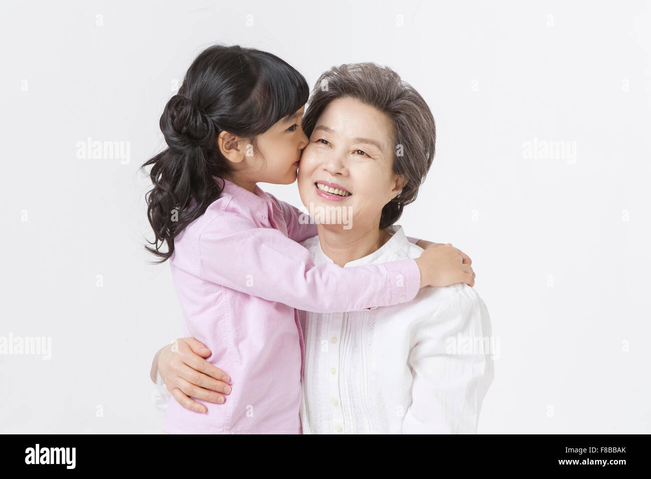 La nipote baciare sulla sua nonna per la guancia e sia sorridente Foto Stock