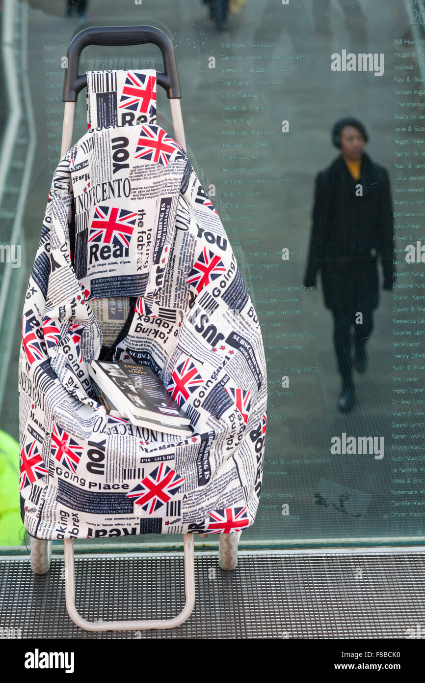 Carrello e libri sul Millennium Bridge con i visitatori a piedi sotto, Londra nel dicembre Foto Stock