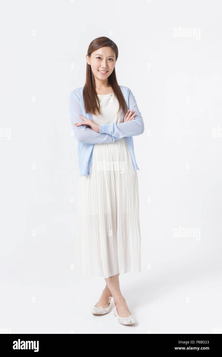 Donna in abito bianco e blu cardigan in piedi con le braccia piegate Foto Stock
