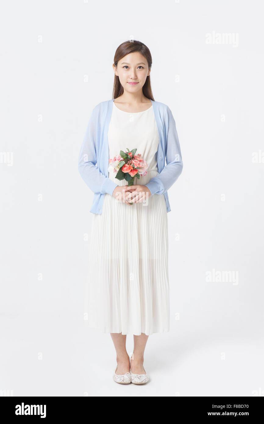 Donna in abito bianco e blu cardigan permanente e la holding fiori Foto Stock