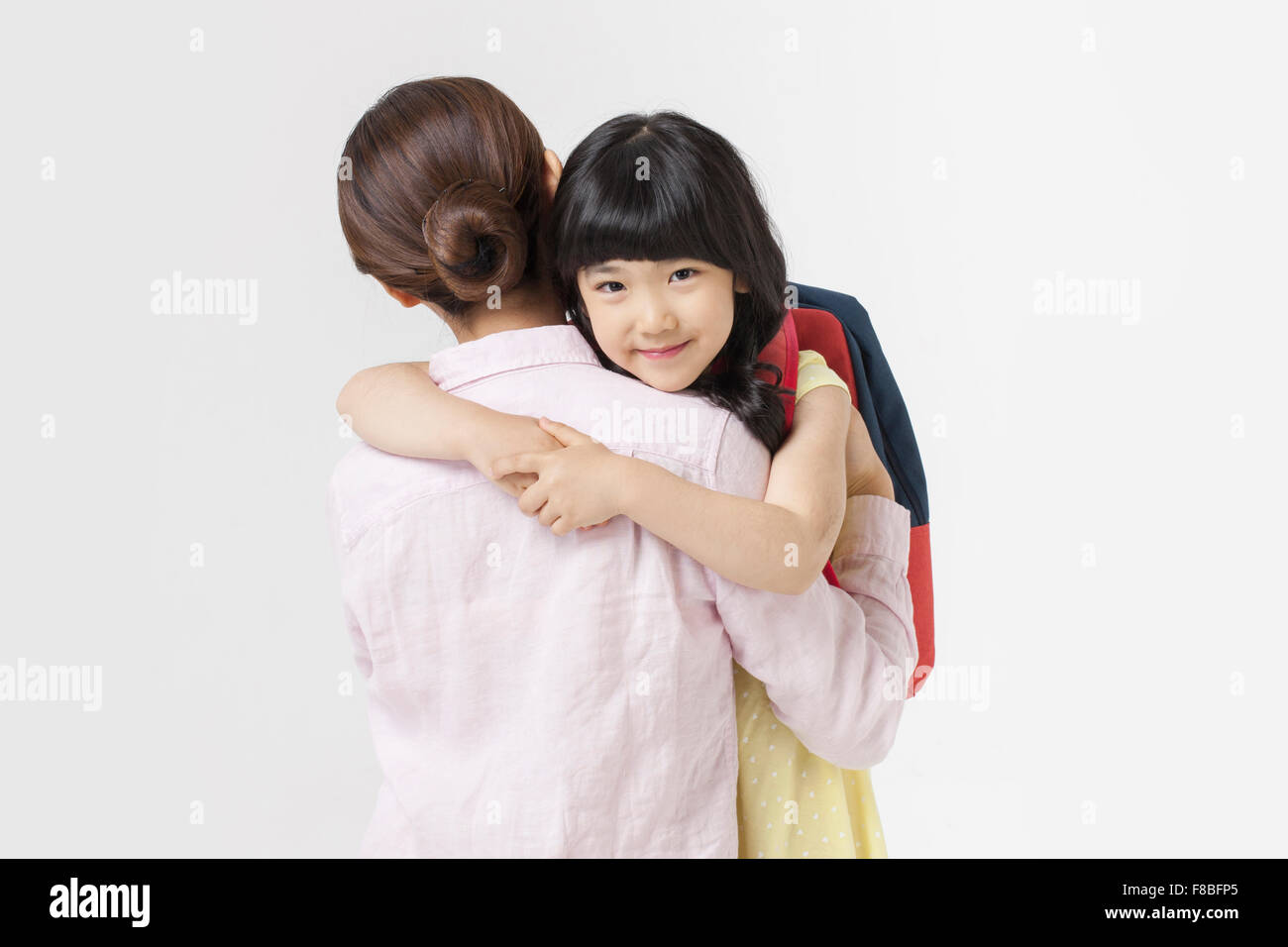 Torna aspetto di madre e figlia abbracciando la sua madre lo sguardo in avanti con un sorriso Foto Stock