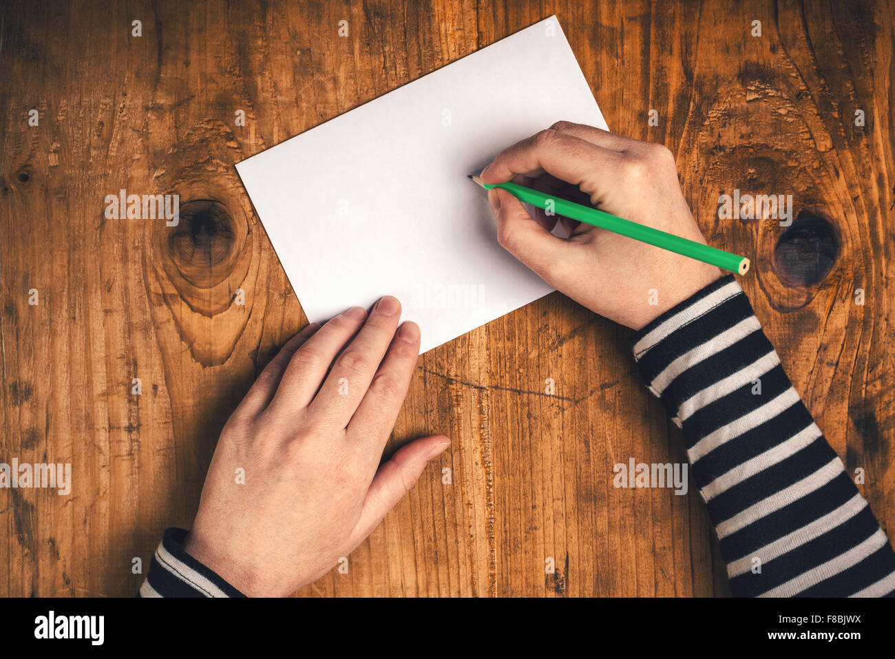 Donna scrivere l'indirizzo del destinatario sulla busta postale, mani femminili dal di sopra sulla scrivania in ufficio invio di lettera, vista dall'alto, toni rétro Foto Stock