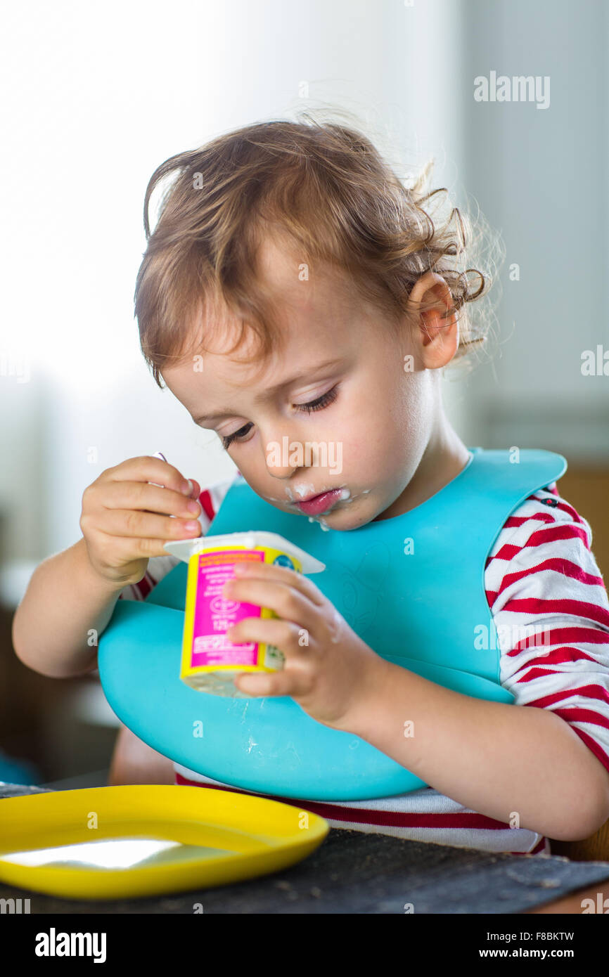 2 anno-vecchio ragazzo di mangiare uno yogurt. Foto Stock
